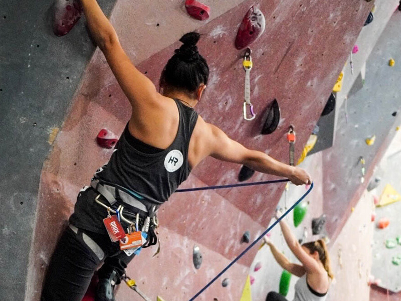 Personne qui grimpe un mur d'escalade, corde à la main